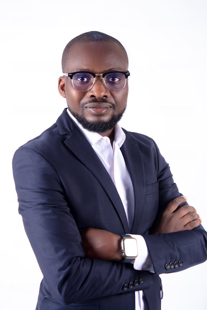 Portrait of a confident businessman wearing a black suit, eyeglasses, and watch on white background.